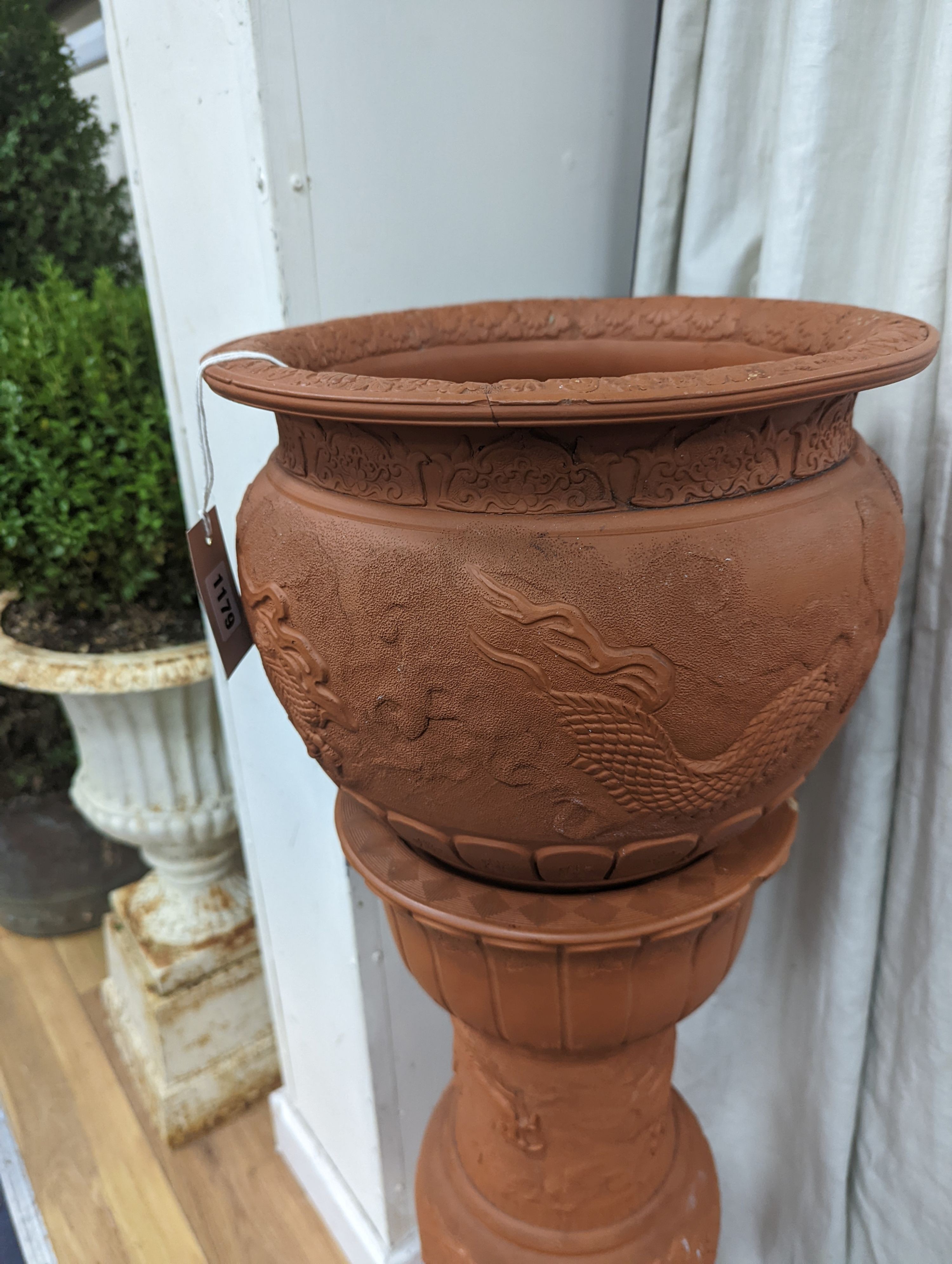 A Chinese earthenware jardiniere on stand moulded with dragons. Height 99 cms.